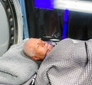 Man in Sechrist hyperbaric chamber covered in blanket.
