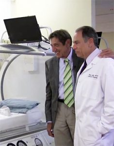 Joe Namath with his doctor looking at one of the hyperbaric oxygen chambers he used to help with his traumatic brain injury.