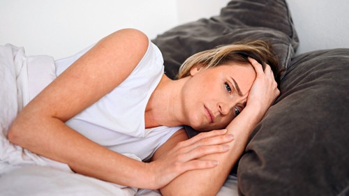 Woman lying in bed with Long Covid fatigue