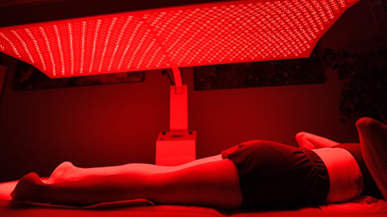 A patient is laying on a red light therapy bed.