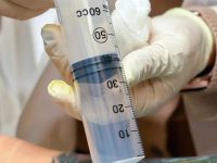 A close-up shot of an AMA doctor performing an Ozone Injection into a patient's lower back.