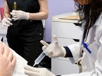 Doctor administering an ozone injection into a patient's elbow for damaged joint repair.