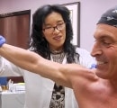 Doctor moves patients arm around after injecting ozone into his shoulder.